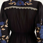 Close-up view of the FARM Rio Black Bold Flowers midi dress from behind, highlighting the intricate blue floral embroidery and geometric lace trim on the upper back yoke.