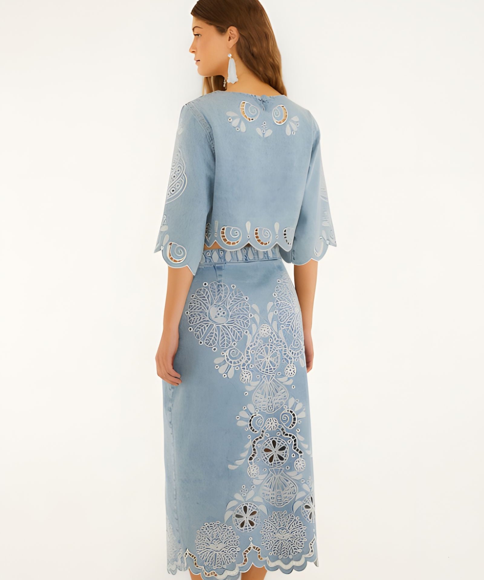 Back view of a model in a studio showcasing the high-rise fit and embroidery details of the FARM Rio denim midi skirt.