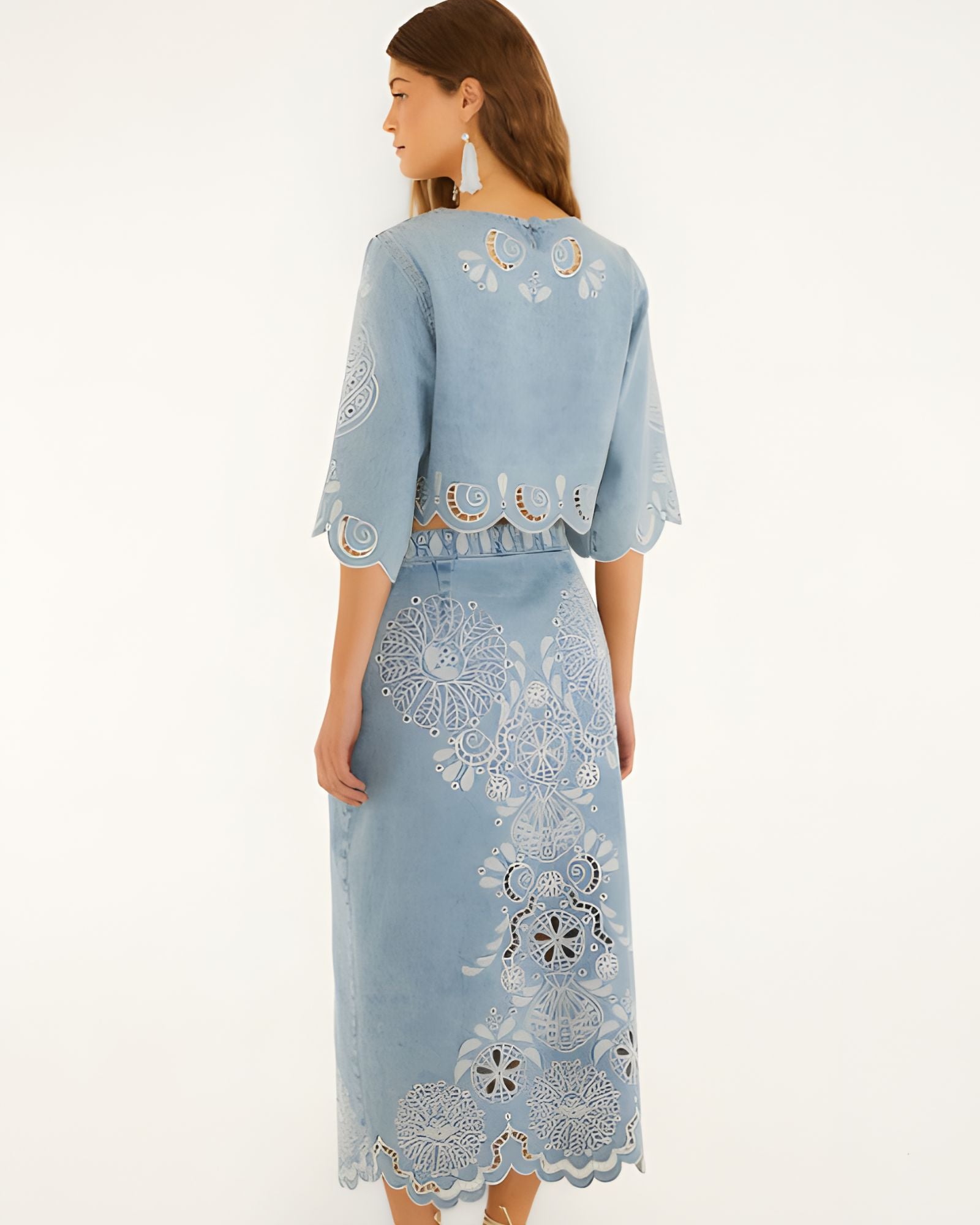Back view of a model in a studio showcasing the high-rise fit and embroidery details of the FARM Rio denim midi skirt.