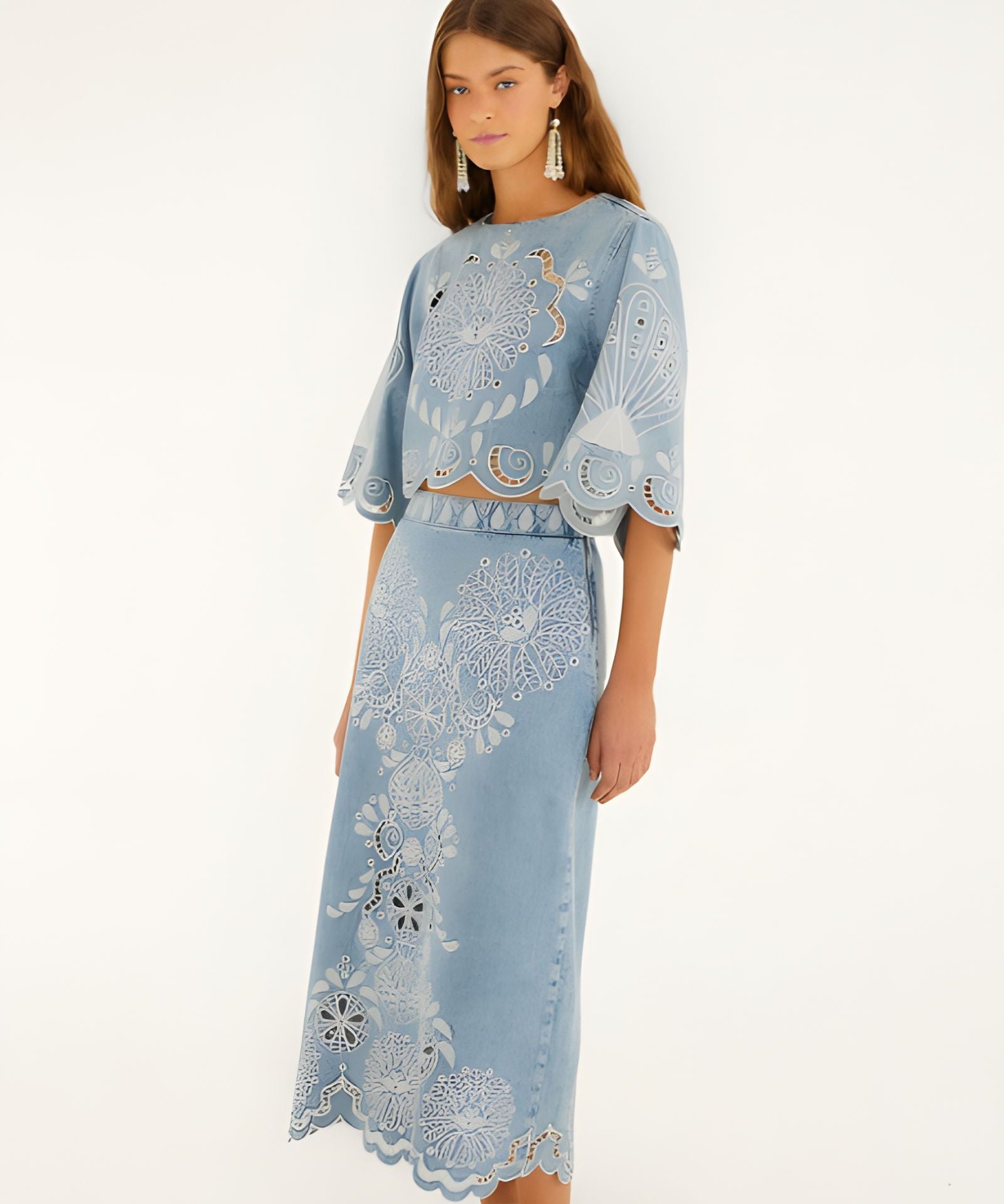 Front view of a model in a studio wearing the Farm Rio denim Richelieu wavy hem midi skirt paired with a matching embroidered top.