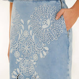 Close-up side view of the Farm Rio denim Richelieu skirt, highlighting the side pocket, zipper closure, and intricate white embroidery.