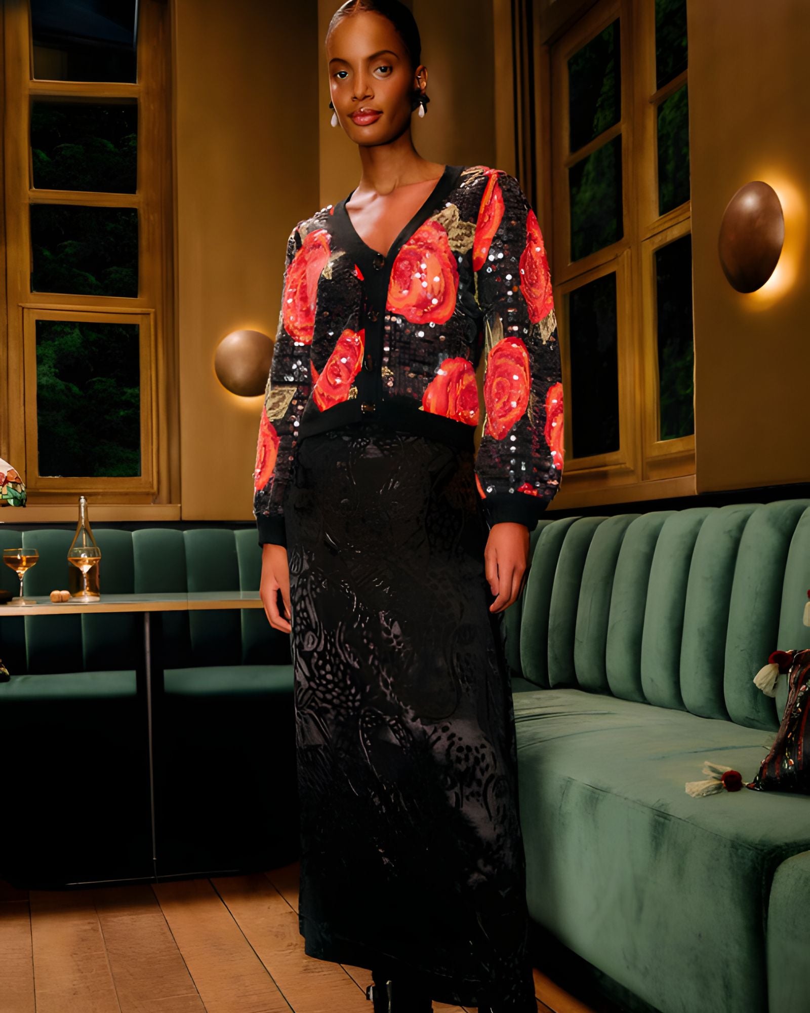 Lifestyle look view of a model in a restaurant setting wearing the FARM Rio Black Midnight Leopards jacquard maxi skirt paired with a floral cardigan.