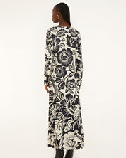 Back view of a model showcasing the continuous black and off-white botanical pattern across the Farm Rio long-sleeve maxi dress.