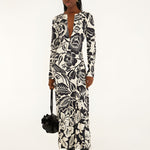 Full-length front view of a model in a studio wearing the Farm Rio Off-White Cashews and Birds viscose maxi dress with long sleeves and a bold graphic print.