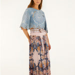 Full body view of a model styling the soft pink Farm Rio pleated maxi skirt with a blue top