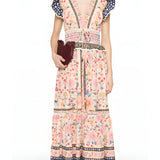 Full-length front view of a model styling the Farm Rio floral tapestry maxi dress, accessorized with a dark clutch bag.