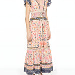 Three-quarter studio view of a model wearing the Farm Rio tapestry printed maxi dress, displaying the elegant drape and tiered skirt layout.