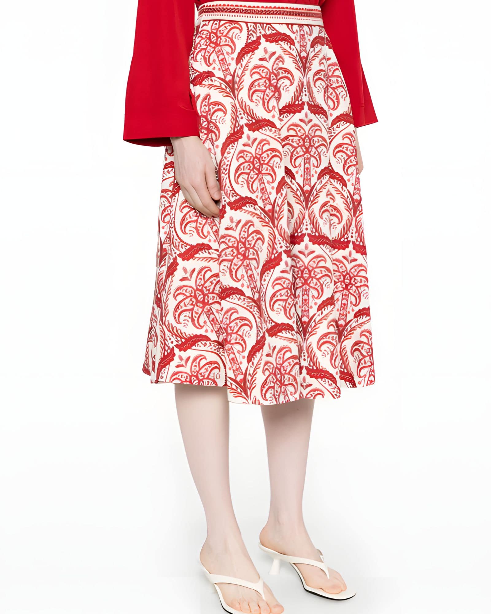 Side studio view of a model wearing the Farm Rio red and white tropical printed midi skirt, paired with a red long-sleeve top.