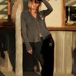 A model leaning against a wooden post outdoors, showcasing the casual streetwear aesthetic and comfortable drape of the charcoal Giulia sweatpants.