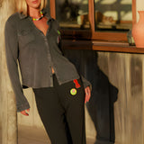 A woman wearing the charcoal carbone Giulia sweatpants, highlighting the relaxed fit and distinct colorful custom patches on the front pocket area.