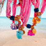 Colorful beaded bandana bracelets with cute crab charms on a beach