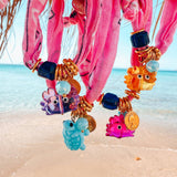 Colorful beaded bandana bracelets with cute crab charms on a beach