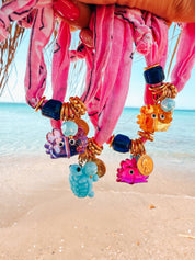 Colorful beaded bandana bracelets with cute crab charms on a beach