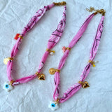 A stacked pile of colorful handmade GOUPI pink bandana necklaces, ready for dispatch from Greece