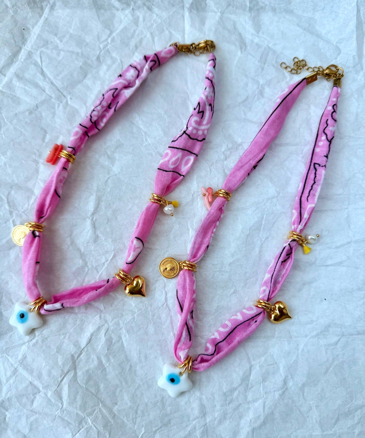 A stacked pile of colorful handmade GOUPI pink bandana necklaces, ready for dispatch from Greece