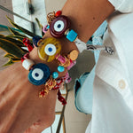 Close-up of a hand wearing colorfu bandana  bracelets with evil eye designs.