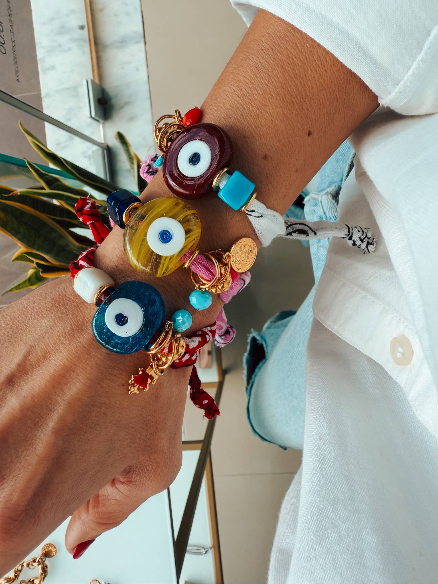 Close-up of a hand wearing colorfu bandana  bracelets with evil eye designs.