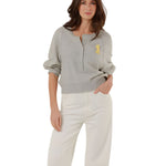 Full-length front view of a model styling the grey fine knit pullover with high-waisted white denim trousers.