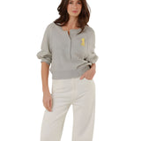 Full-length front view of a model styling the grey fine knit pullover with high-waisted white denim trousers.