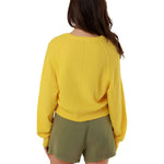 Direct back view of the yellow Keila knit pullover, showcasing the clean draped silhouette and fine ribbed hemline finish.