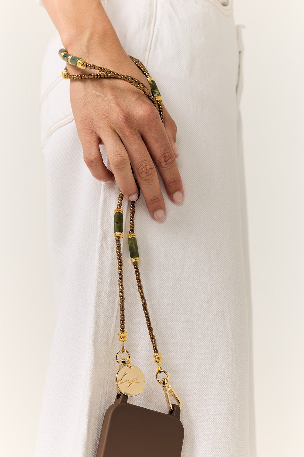 La Coque Française Izzie sage green phone chain worn crossbody with a white outfit