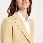 Side angle close-up focusing on the mid-width notched lapel structure, relaxed shoulder fit, and gold statement earrings.