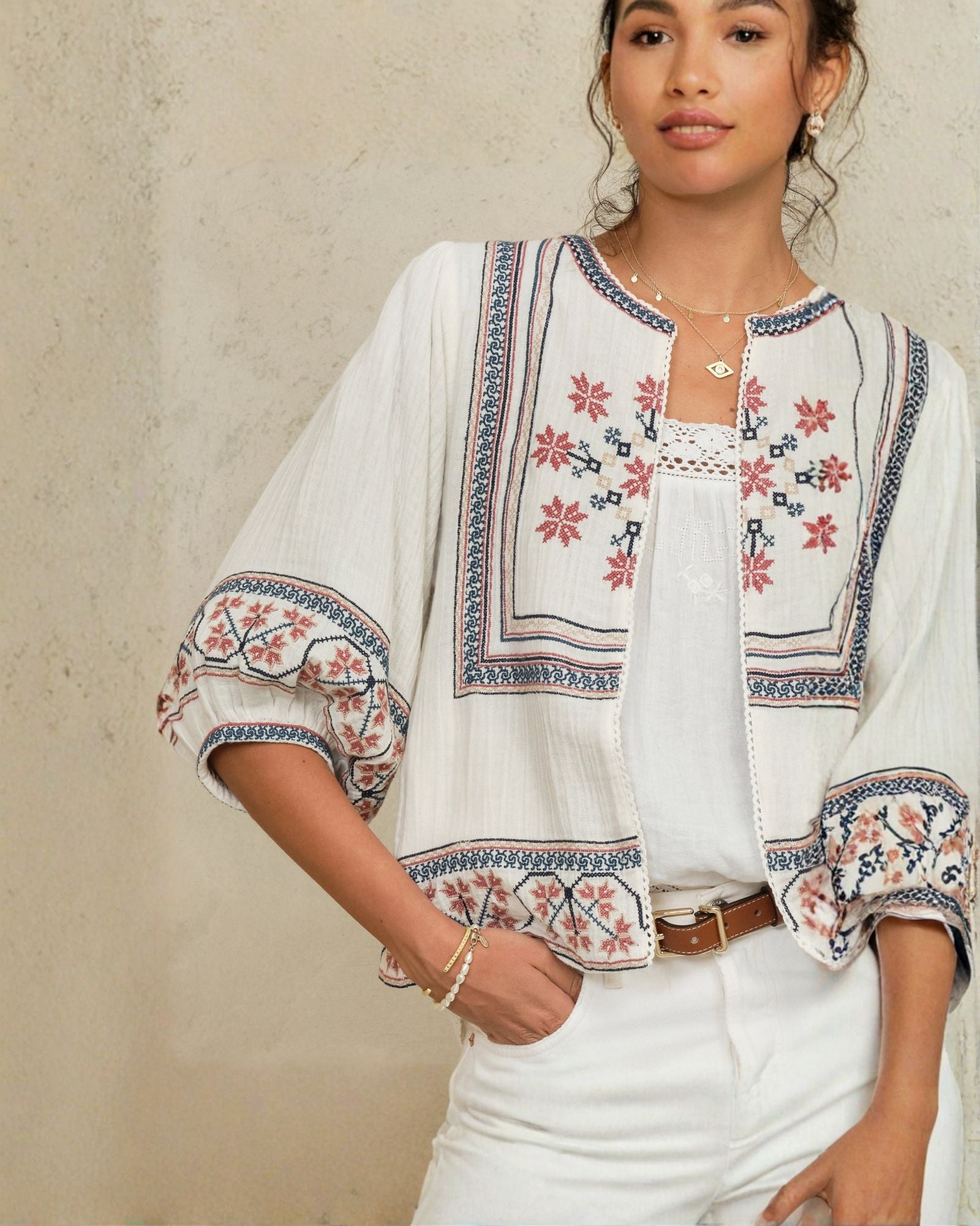 Close-up view of the red and blue geometric floral embroidery on a white Mabe Apparel cotton jacket.