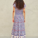 Back view of the tiered Mabe Apparel Della maxi dress in blue and pink artisan print on a model.