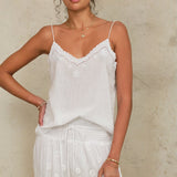 Model wearing a Mabe Apparel white embroidered strappy top paired with a matching tiered skirt.