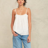 Woman wearing a Mabe Apparel white embroidered cotton camisole with blue jeans.