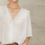 Close-up of white lace cotton blouse by Mabe Apparel featuring lace trim and V-neckline.