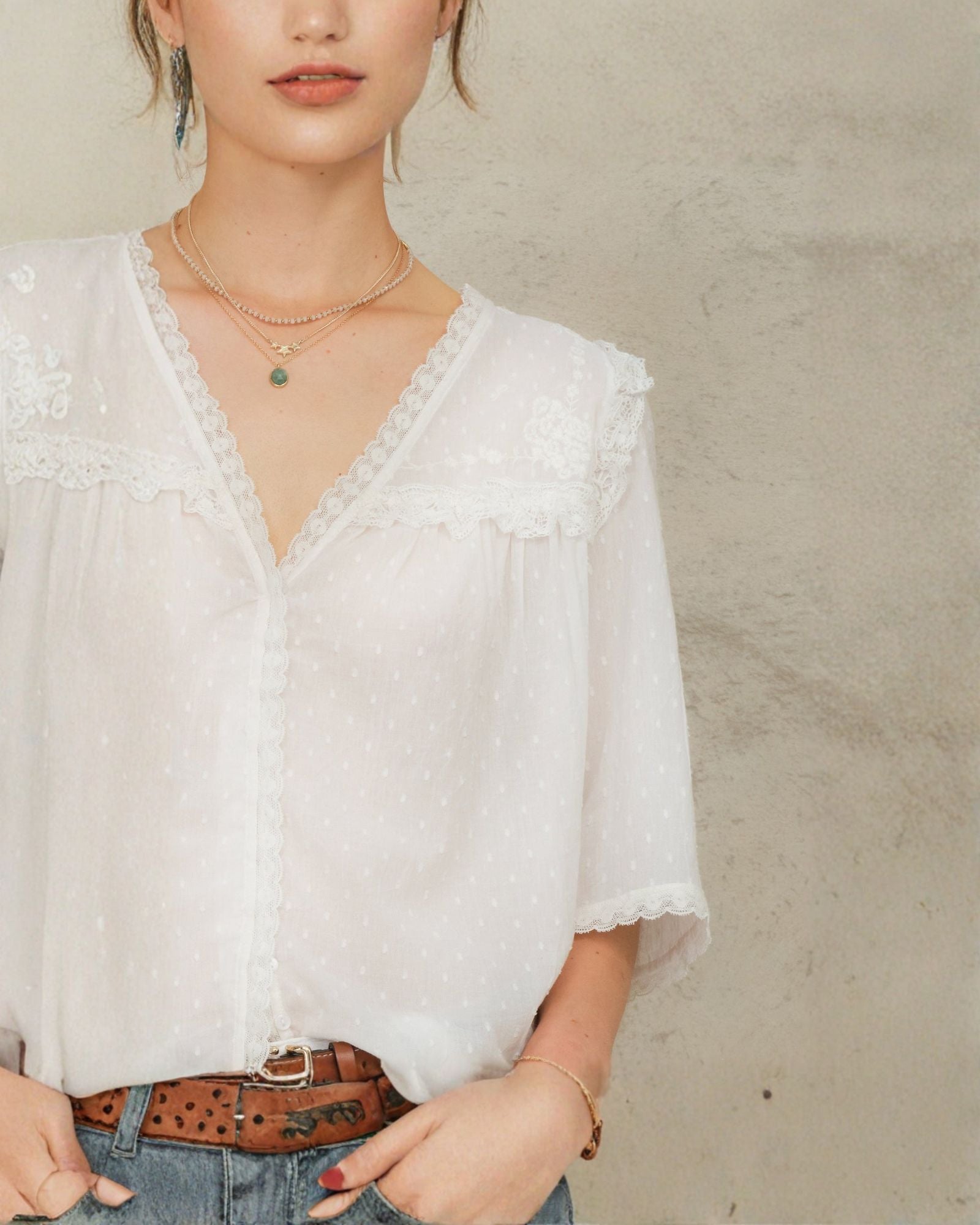 Close-up of white lace cotton blouse by Mabe Apparel featuring lace trim and V-neckline.