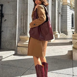 Woman wearing MICUIR Mestizo burgundy cowboy boots with a camel coat dress