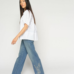 White MMTarima cotton blouse side view on model, paired with denim jeans