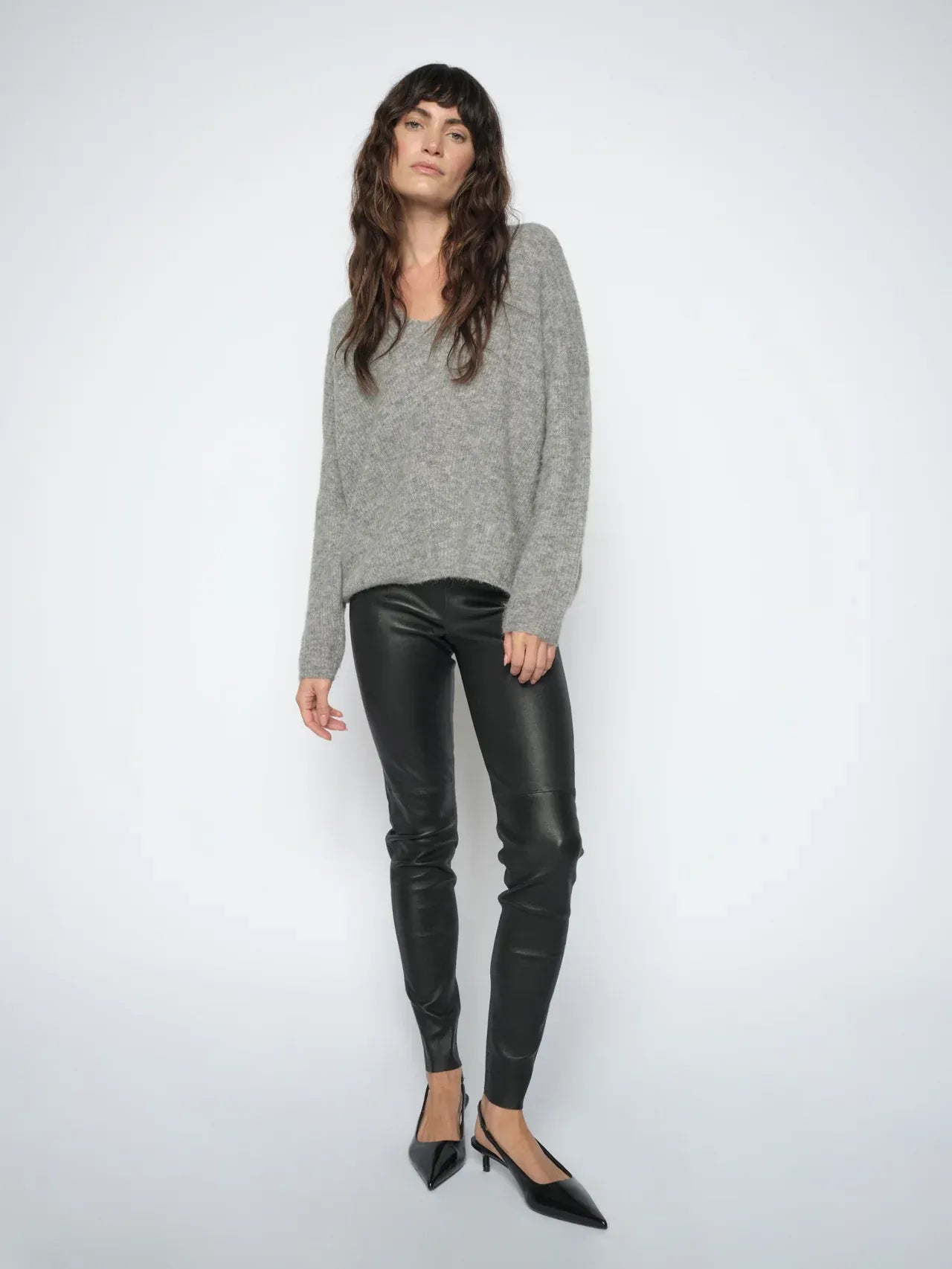 Woman wearing the  Mos Mosh MMSarina black leather leggings styled with a grey knit and black pointed heels.