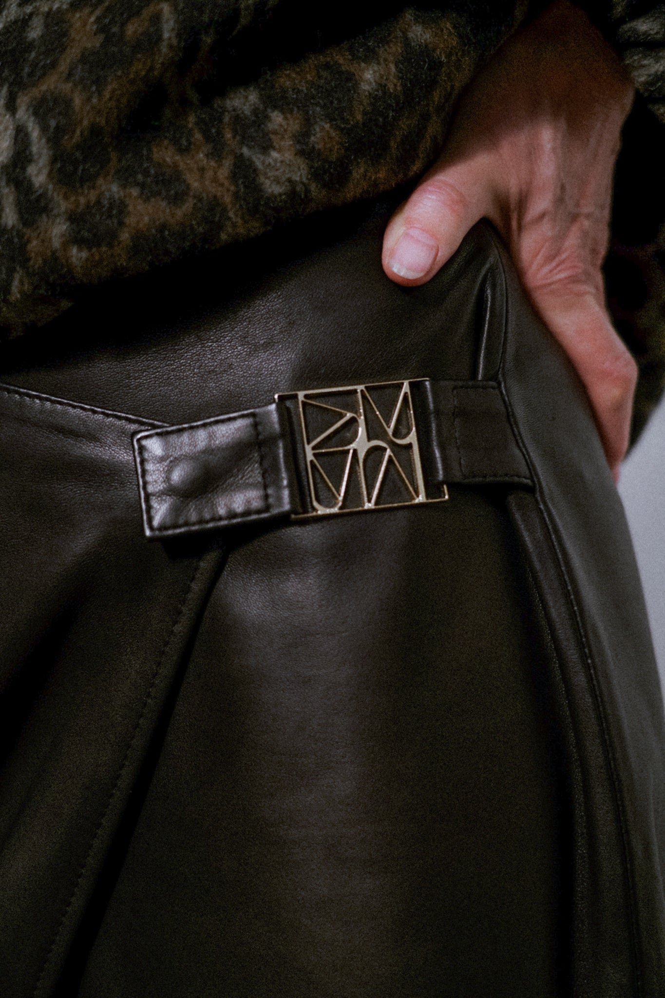 MOS MOSH Vela leather wrap skirt in black, close-up of the a sculpted metal buckle
