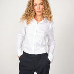 Woman wearing the slim-fit white MMTilda shirt and dark pants for  a polished office look, 