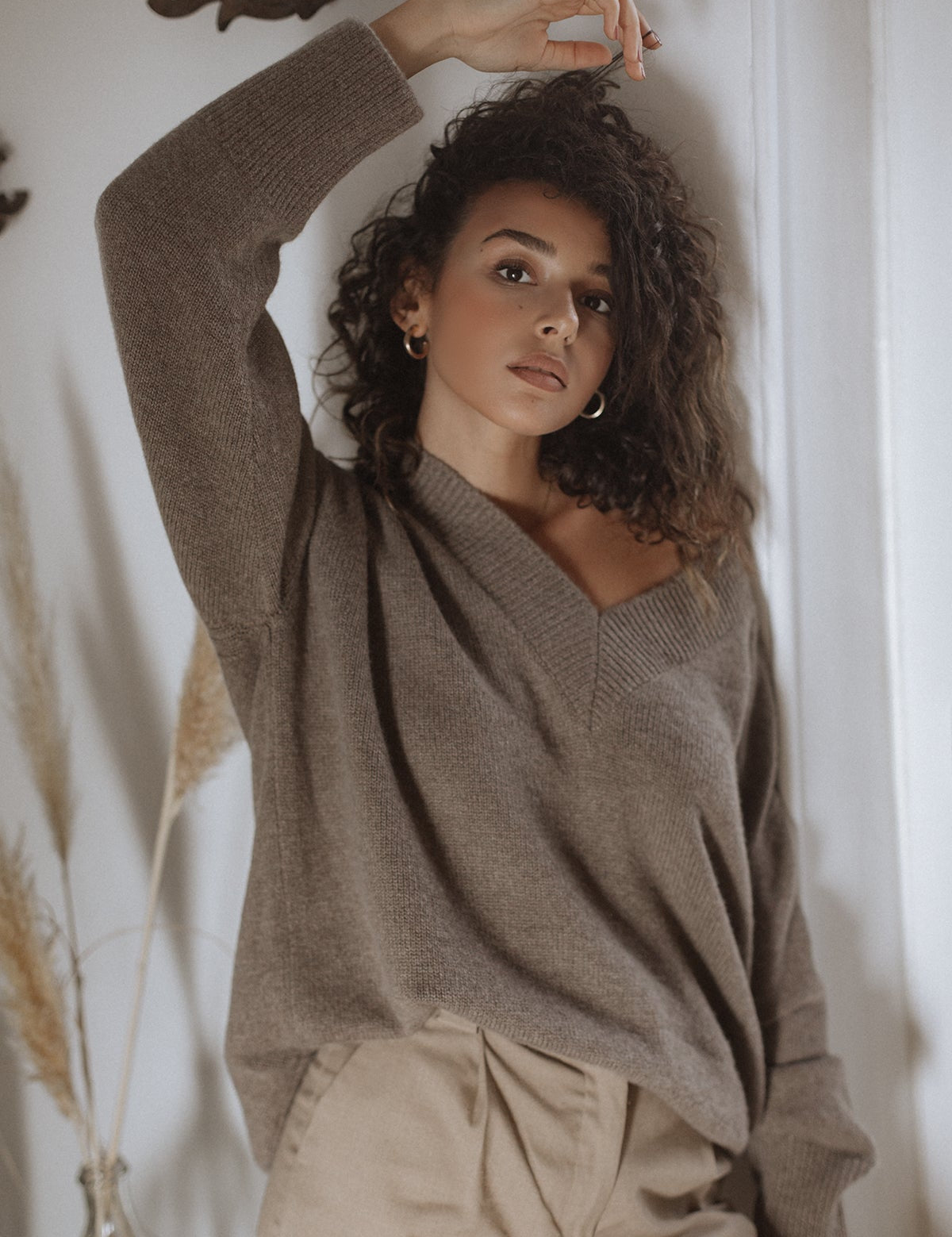 Model wears the relaxed-fit Nuage natural brown baby cashmere V-neck, styled with high-waisted beige trousers.