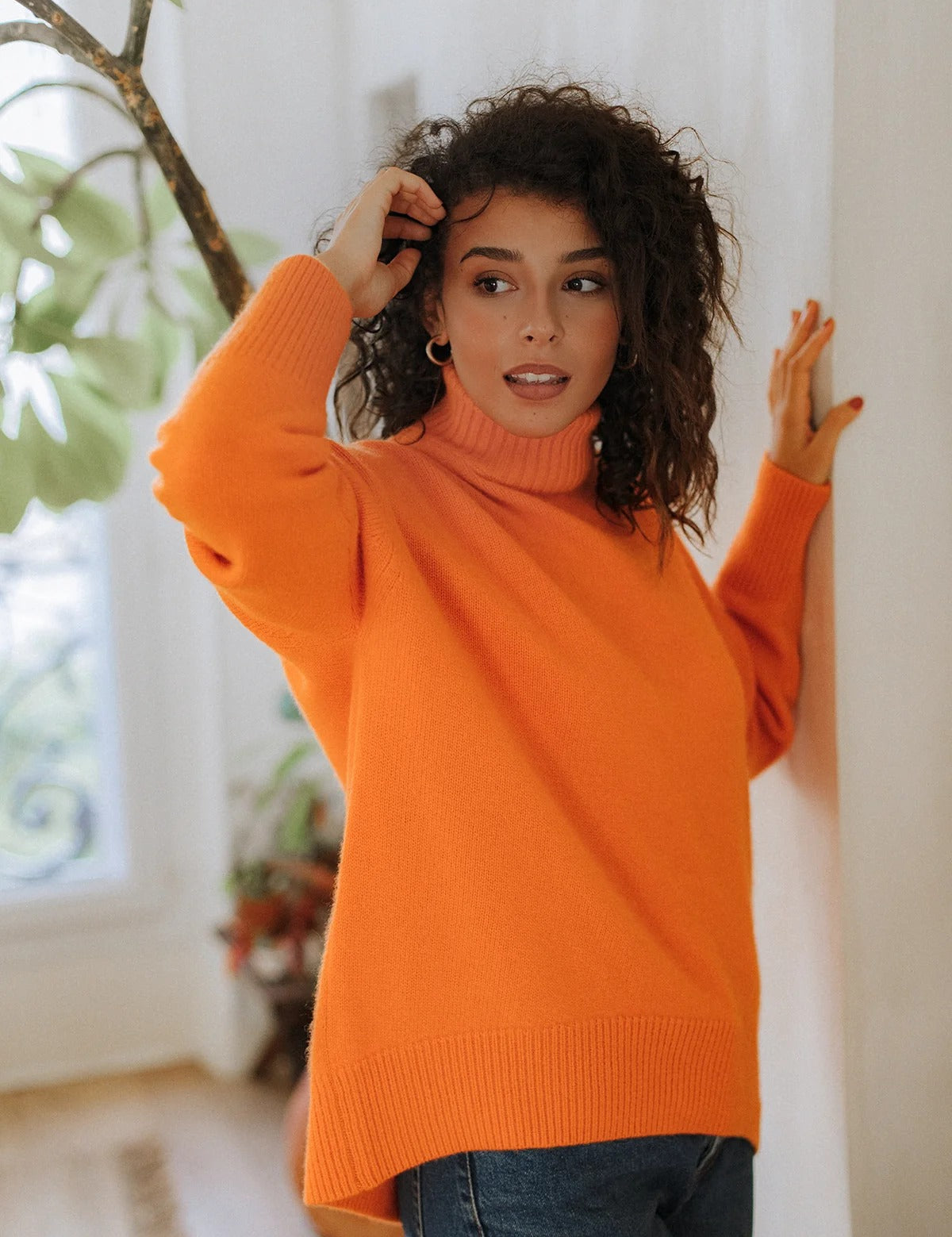 Woman wearing the vibrant Arancia orange turtleneck by Nuage Cashmere—your new favorite for the Swiss chalet lifestyle