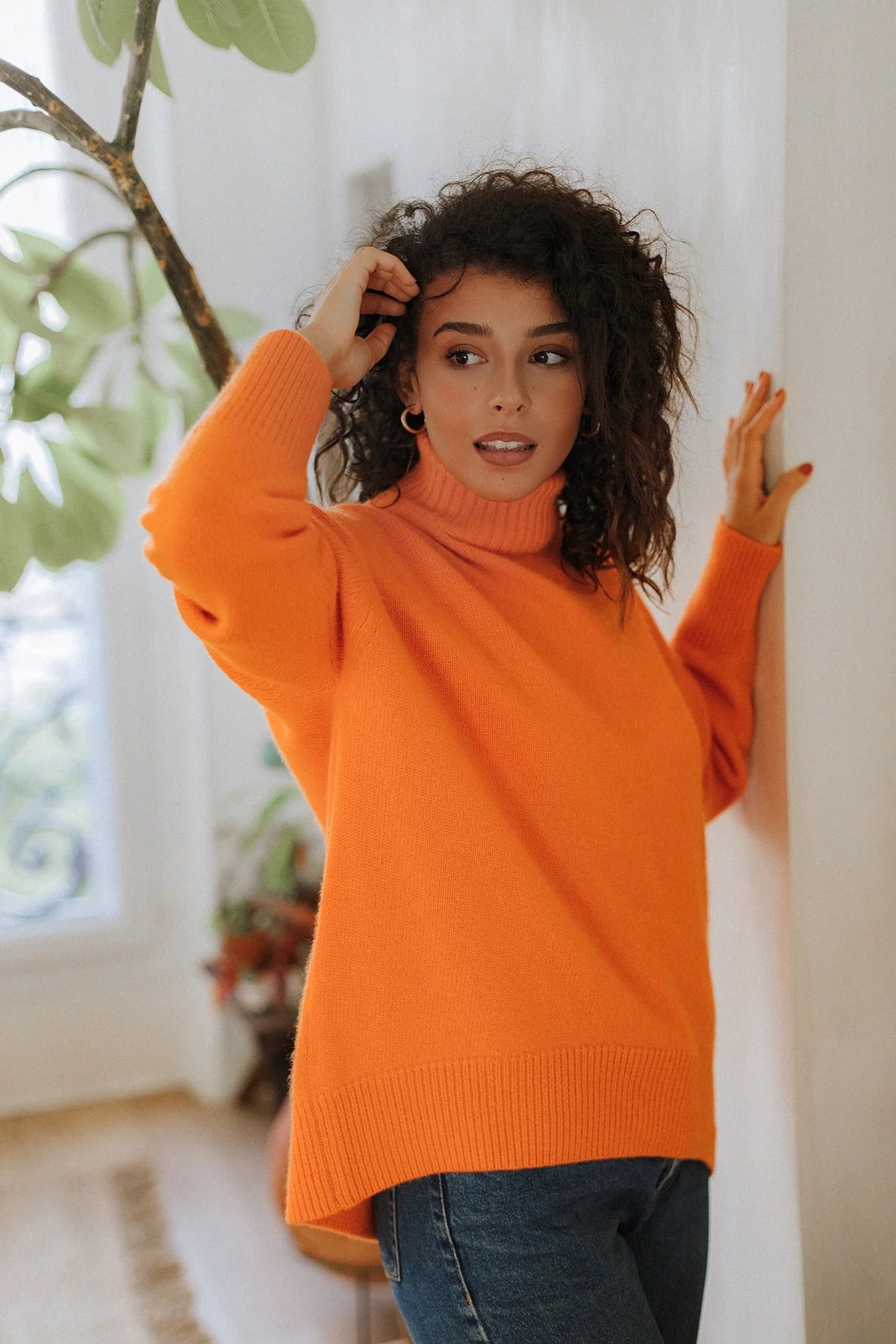 Woman wearing the vibrant Arancia orange turtleneck by Nuage Cashmere—your new favorite for the Swiss chalet lifestyle