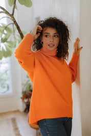 Woman wearing the vibrant Arancia orange turtleneck by Nuage Cashmere—your new favorite for the Swiss chalet lifestyle