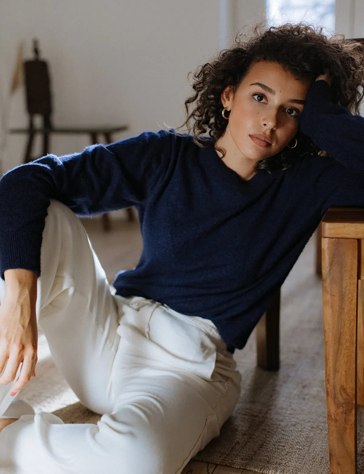 A woman wearing a classic navy crew neck cashmere sweater styled for a casual luxury look