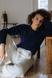 A woman wearing a classic navy crew neck cashmere sweater styled for a casual luxury look