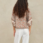 Back view of a model showcasing the fit of a cream and coral red printed block jacket by Mabe Apparel.