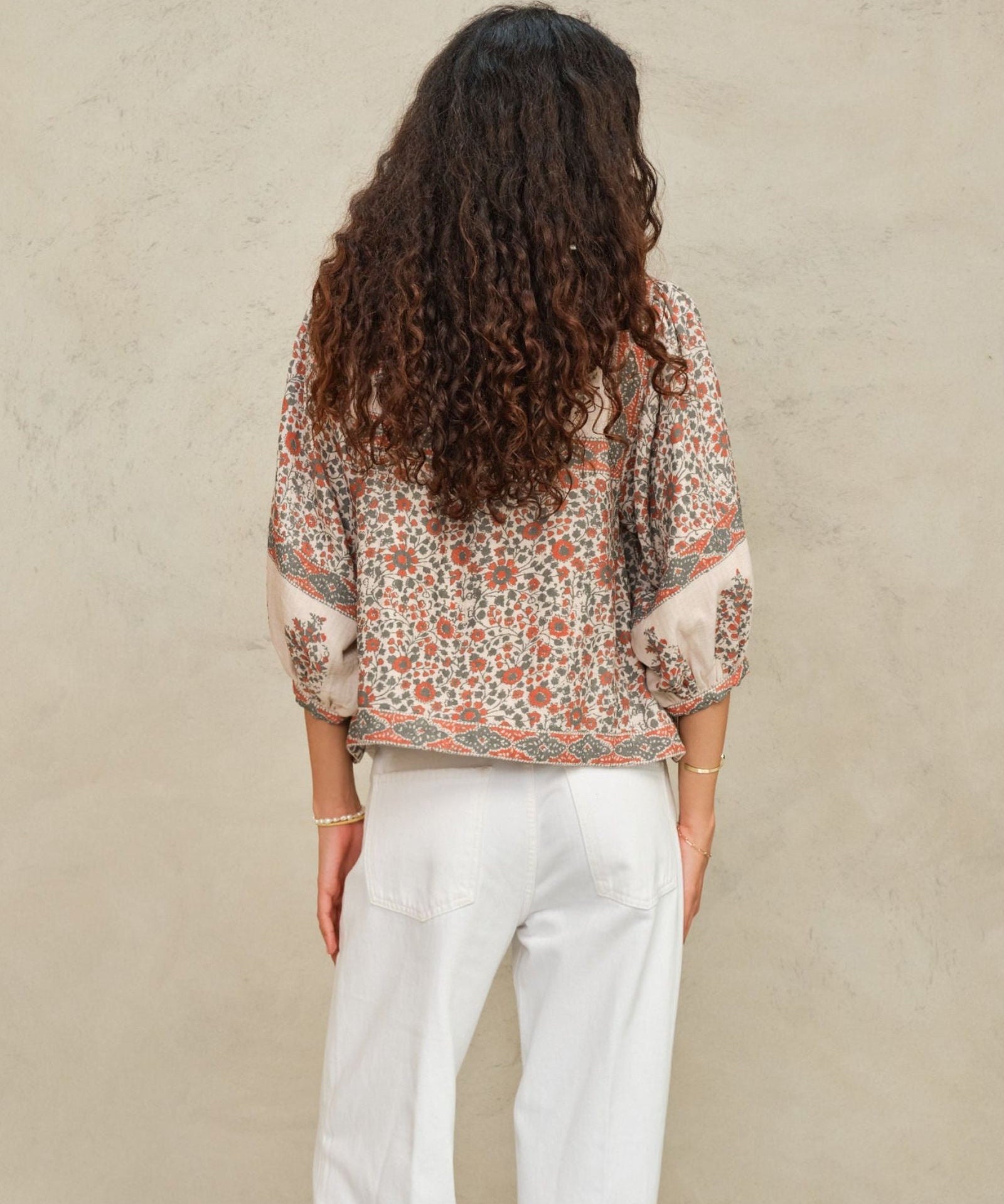Back view of a model showcasing the fit of a cream and coral red printed block jacket by Mabe Apparel.