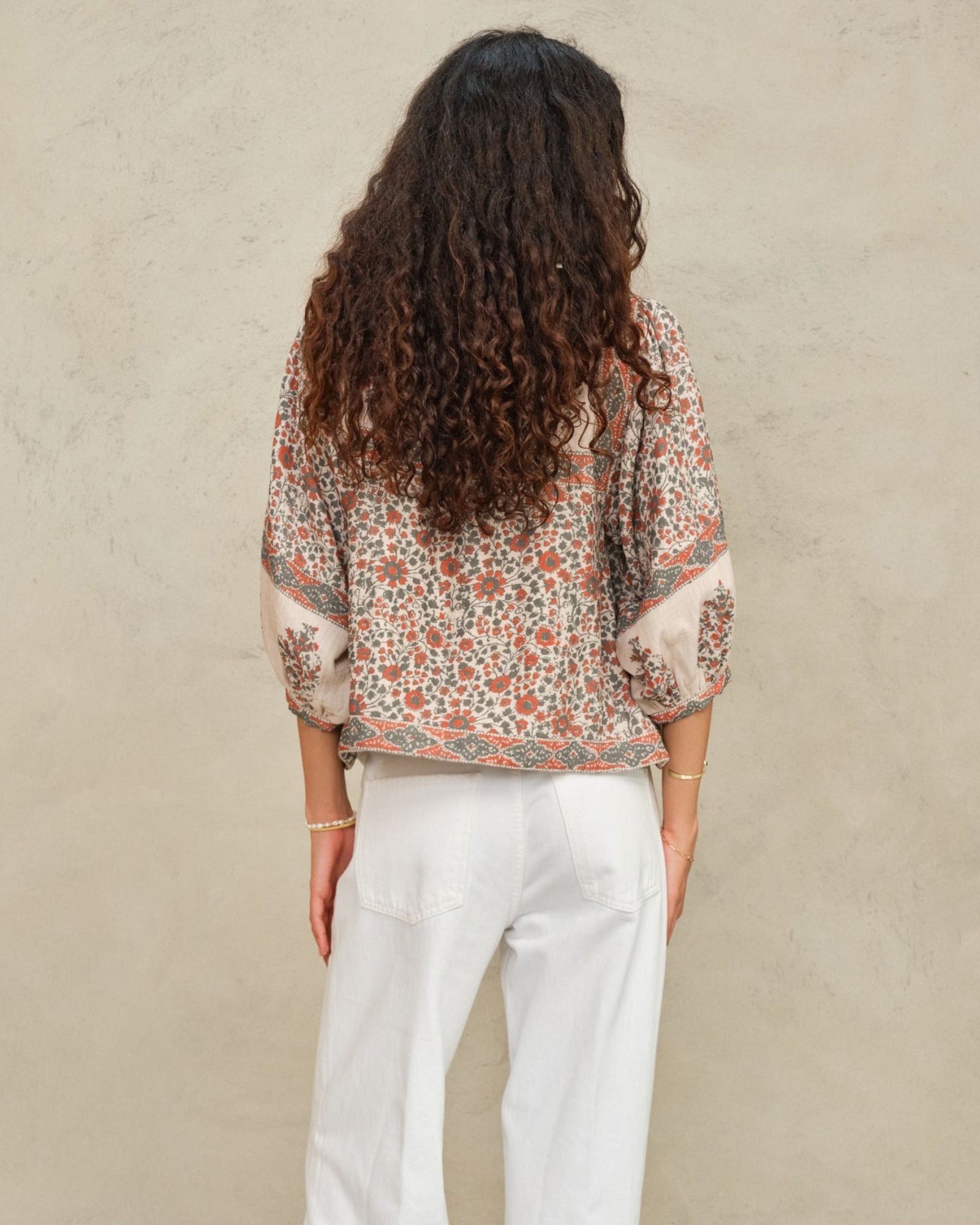 Back view of a model showcasing the fit of a cream and coral red printed block jacket by Mabe Apparel.