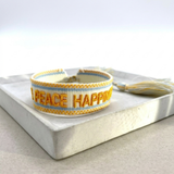 Cream woven Parsley & Pepper bracelet with mustard-yellow “LOVE PEACE HAPPINESS” embroidery, yellow and light blue borders – second view.