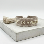 Close-up of adjustable woven statement bracelet with embroidered “MINDSET IS EVERYTHING” lettering and sliding knot tassel cords.