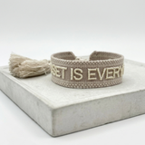 Close-up of adjustable woven statement bracelet with embroidered “MINDSET IS EVERYTHING” lettering and sliding knot tassel cords.
