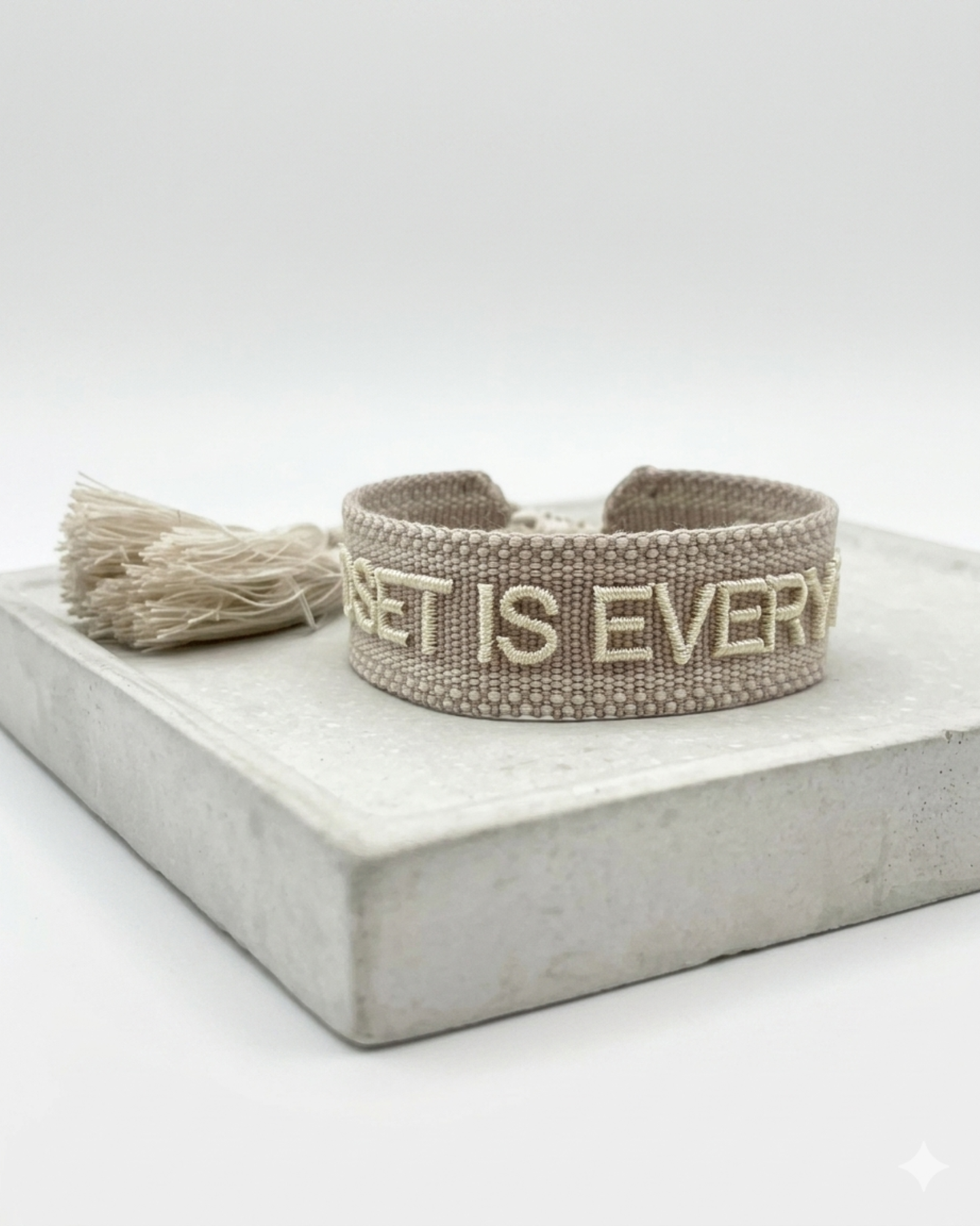 Close-up of adjustable woven statement bracelet with embroidered “MINDSET IS EVERYTHING” lettering and sliding knot tassel cords.
